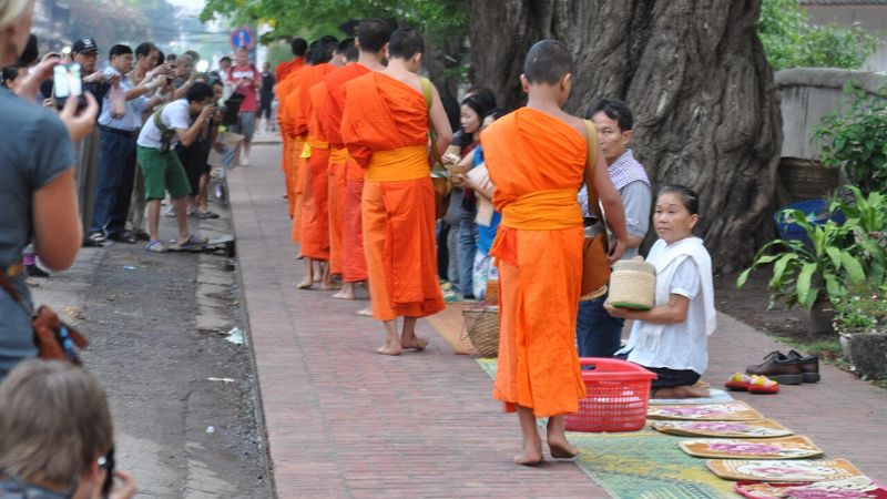 Woman offering food to a novice monk on the morning alms round