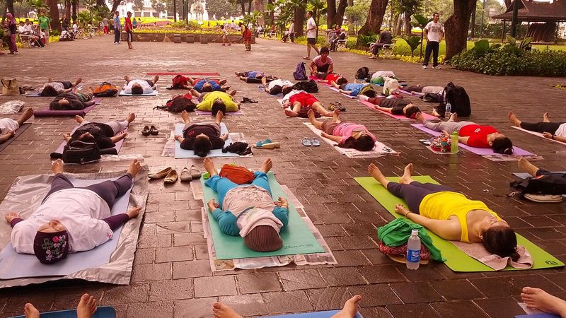 A group resting in savasana outdoors in Jakarta